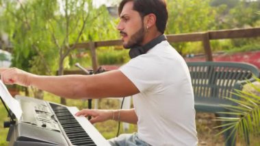 Beyaz gömlekli çocuk dışarıdaki doğada piyano çalıyor..