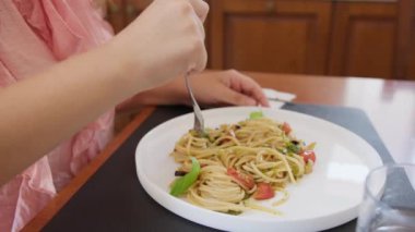 İki genç İtalyan kadın mutfaktaki masada yemek yiyorlar.