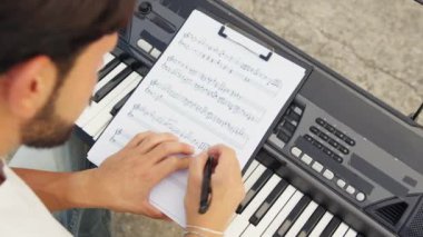 Beyaz gömlekli çocuk dışarıdaki doğada piyano çalıyor..