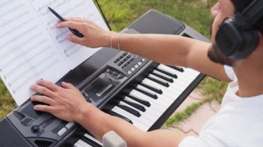 Beyaz gömlekli çocuk dışarıdaki doğada piyano çalıyor..