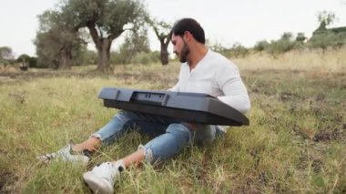 Beyaz gömlekli çocuk dışarıdaki doğada piyano çalıyor..