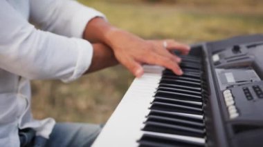 Beyaz gömlekli çocuk dışarıdaki doğada piyano çalıyor..