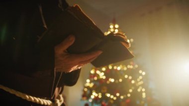 Dindar keşiş Noel Gecesinde Ağacın önünde Açık İncille dua eder.