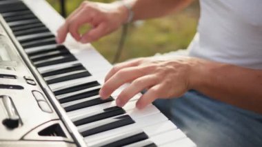 Beyaz gömlekli çocuk dışarıdaki doğada piyano çalıyor..