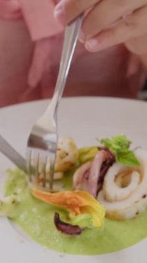 İki genç İtalyan kadın mutfaktaki masada yemek yiyorlar.