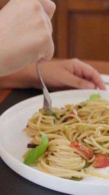 İki genç İtalyan kadın mutfaktaki masada yemek yiyorlar.