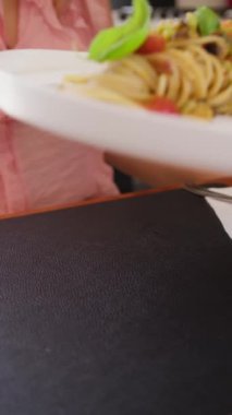 İki genç İtalyan kadın mutfaktaki masada yemek yiyorlar.