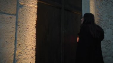 Gizemli genç kadın pelerin ve fenerle bir köyün sokaklarında yürüyor..