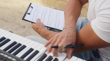 Beyaz gömlekli çocuk dışarıdaki doğada piyano çalıyor..