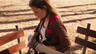 Sahilin yanındaki doğada bas gitar çalan bir kız..