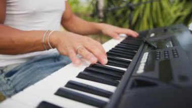 Beyaz gömlekli çocuk dışarıdaki doğada piyano çalıyor..