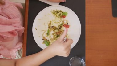 İki genç İtalyan kadın mutfaktaki masada yemek yiyorlar.