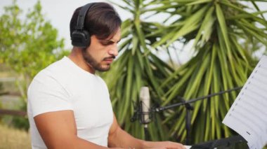 Beyaz gömlekli çocuk dışarıdaki doğada piyano çalıyor..