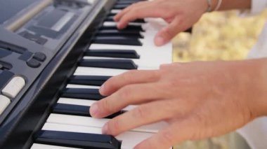 Beyaz gömlekli çocuk dışarıdaki doğada piyano çalıyor..