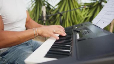 Beyaz gömlekli çocuk dışarıdaki doğada piyano çalıyor..