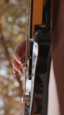 Sahilin yanındaki doğada bas gitar çalan bir kız..