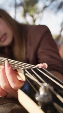 Sahilin yanındaki doğada bas gitar çalan bir kız..