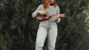 Mutlu kız doğada gitar çalıyor..