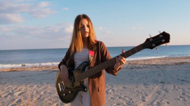 Sahilin yanındaki doğada bas gitar çalan bir kız..