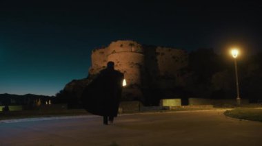 Gizemli genç kadın pelerin ve fenerle bir köyün sokaklarında yürüyor..