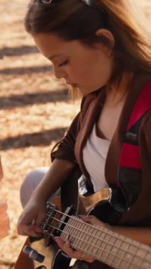 Sahilin yanındaki doğada bas gitar çalan bir kız..
