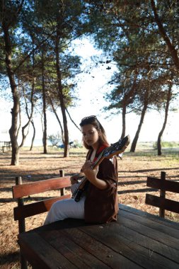 Sahilin yanındaki doğada bas gitar çalan bir kız..