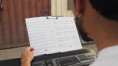 Beyaz gömlekli çocuk dışarıdaki doğada piyano çalıyor..