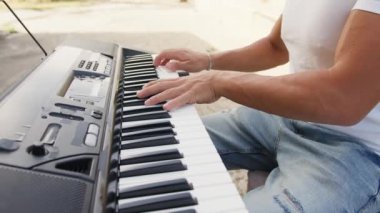 Beyaz gömlekli çocuk dışarıdaki doğada piyano çalıyor..