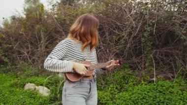 Mutlu kız doğada gitar çalıyor..