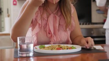 İki genç İtalyan kadın mutfaktaki masada yemek yiyorlar.