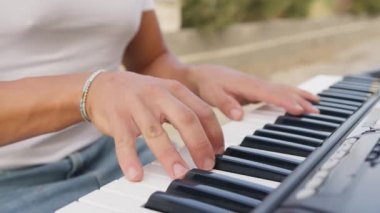 Beyaz gömlekli çocuk dışarıdaki doğada piyano çalıyor..