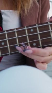 Sahilin yanındaki doğada bas gitar çalan bir kız..