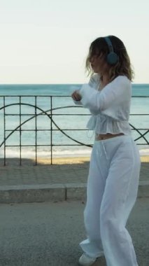 Yazın plajda beyazlar içinde dans eden genç bir kadın.