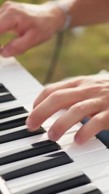 Beyaz gömlekli çocuk dışarıdaki doğada piyano çalıyor..