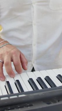 Beyaz gömlekli çocuk dışarıdaki doğada piyano çalıyor..