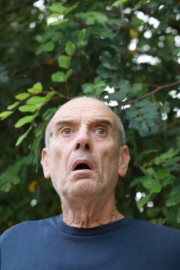 Yaşlı beyaz adam farklı bir yüz ifadesi takınıyor..