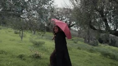 Bulutlu bir günde kırsalda pelerinli genç bir kadın..