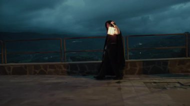 Bulutlu bir günde kırsalda pelerinli genç bir kadın..