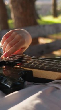 Sahilin yanındaki doğada bas gitar çalan bir kız..