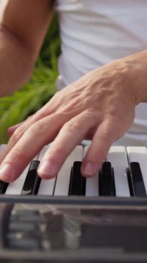 Beyaz gömlekli çocuk dışarıdaki doğada piyano çalıyor..