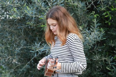 Mutlu kız doğada gitar çalıyor..