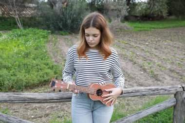 Mutlu kız doğada gitar çalıyor..