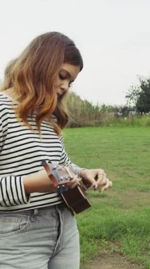 Mutlu kız doğada gitar çalıyor..