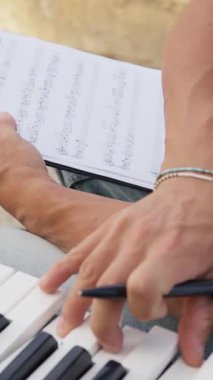 Beyaz gömlekli çocuk dışarıdaki doğada piyano çalıyor..