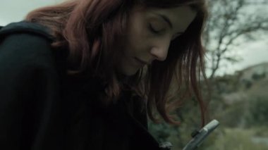 Bulutlu bir günde kırsalda pelerinli genç bir kadın..