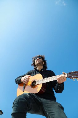 Adam parktaki bir günlük ayakta klasik gitar çalıyor..