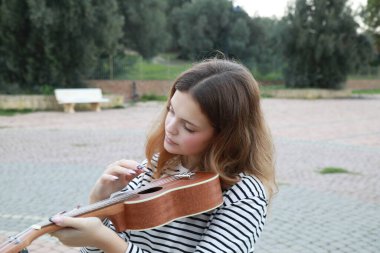 Mutlu kız doğada gitar çalıyor..