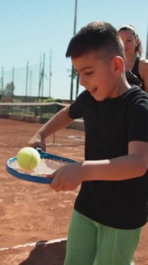 Bayan eğitmen, gündüz vakti Clay Court 'ta tenis öğretiyor..