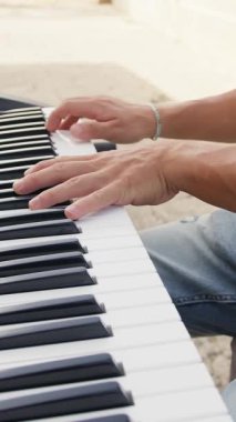 Beyaz gömlekli çocuk dışarıdaki doğada piyano çalıyor..