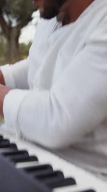 Beyaz gömlekli çocuk dışarıdaki doğada piyano çalıyor..